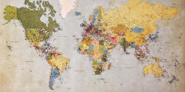 A wold map with pins in it.